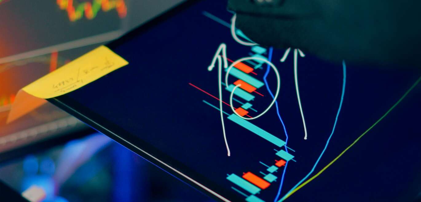 Investor analyzing stock market charts on tablet and laptop